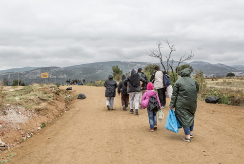 Refugees and migrants walking the dusty road in the rain to the reception center of Presevo, Serbia